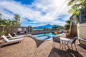 A pool area with lounge chairs, a small pool, and a covered seating area.