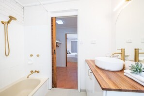 A modern bathroom with a bathtub, a shower, and a sink with gold fixtures.