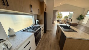 Une cuisine moderne équipée d’une cuisinière à gaz, d’un four et d’un lave-vaisselle, de meubles en bois et d’un plan de travail en marbre.