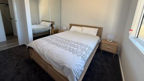 Une chambre à coucher avec un grand lit, une table de chevet, un miroir et une fenêtre.