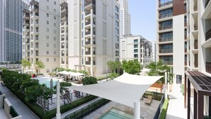 Um edifício residencial moderno com várias varandas, uma piscina no terraço e vegetação ao redor.
