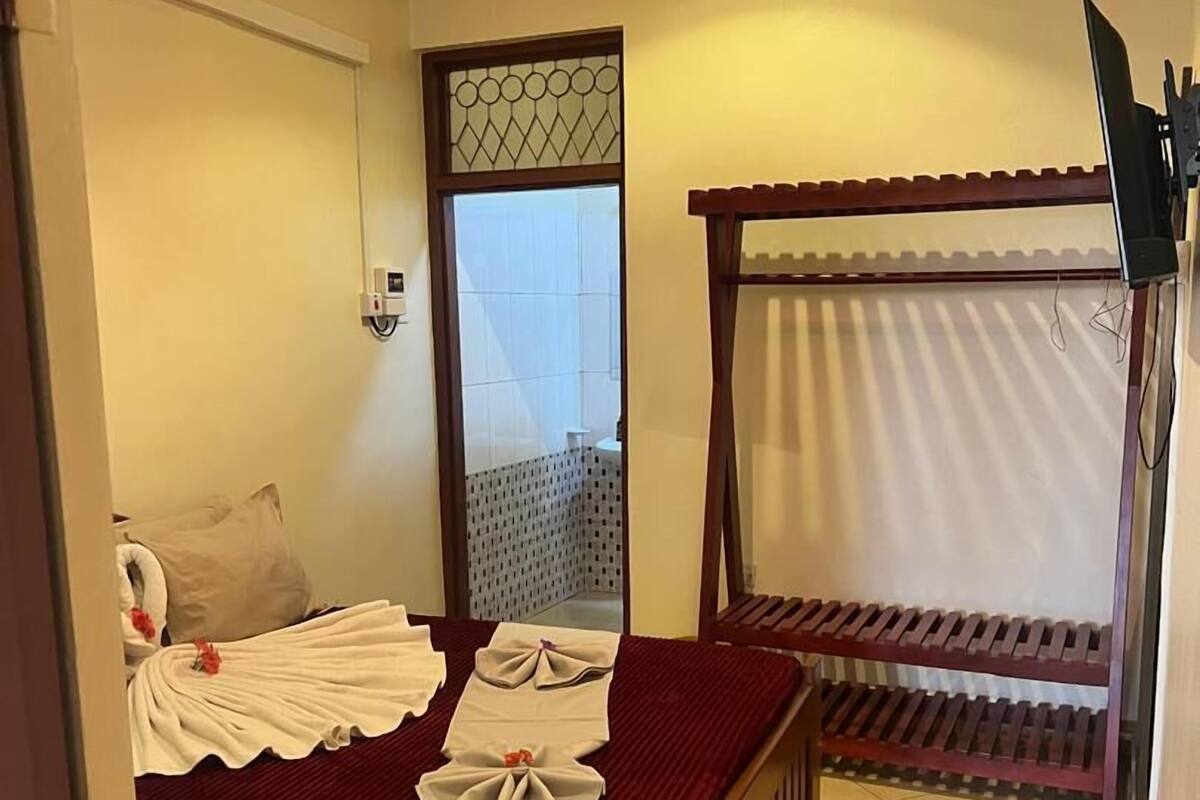 A hotel room with a bed, a ceiling fan, a window, and a view of the outside.