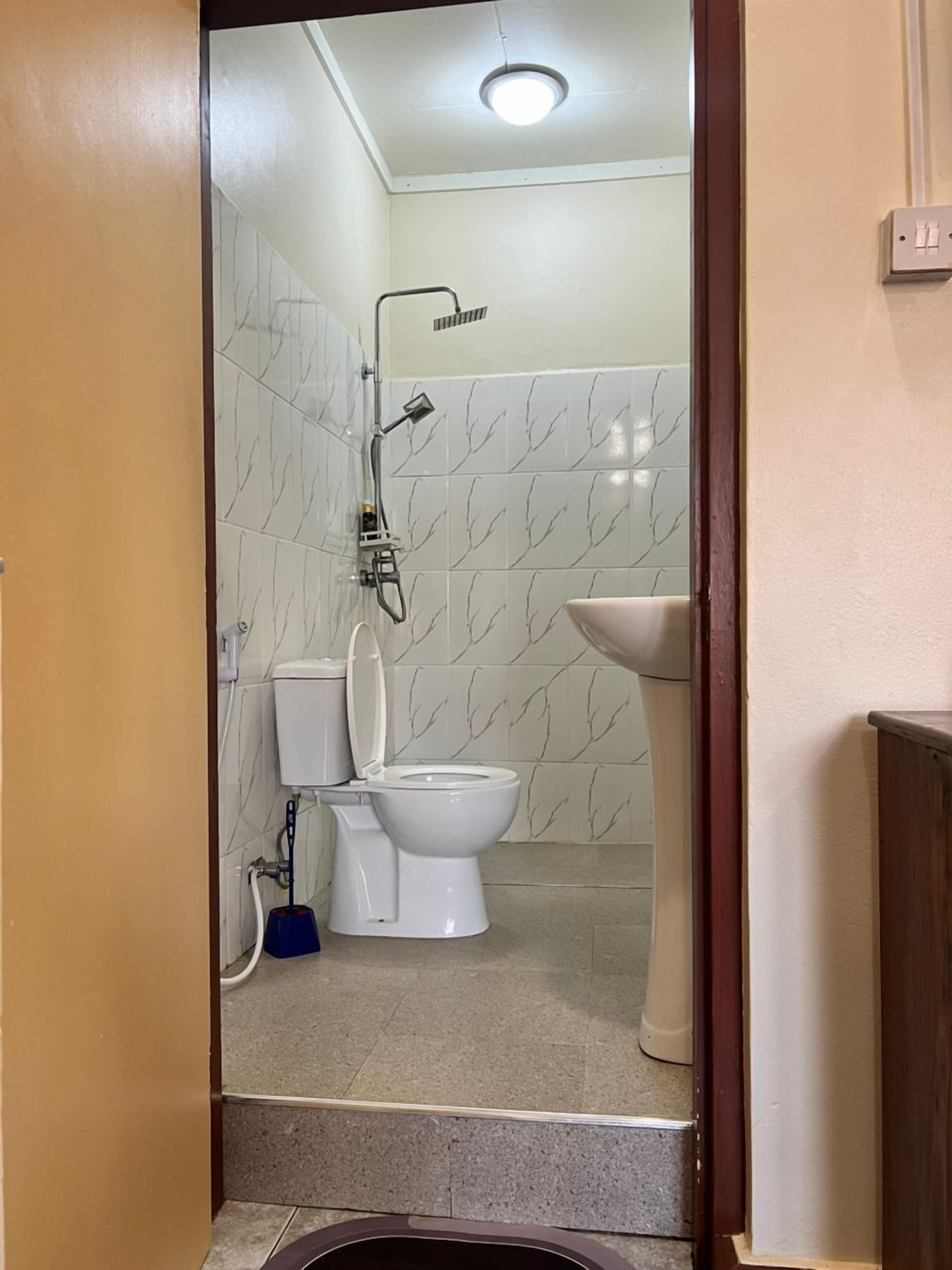 A bathroom with a toilet, a shower, and a sink.