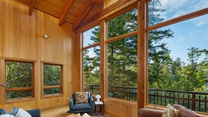 A spacious room with large windows, a leather sofa, a chair, and a wooden coffee table.