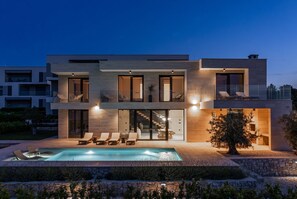 A modern two-story house with a swimming pool, lounge chairs, and a well-lit exterior. - Villa Belvedere 2 Zadarvillas (Sveti Filip i Jakov)