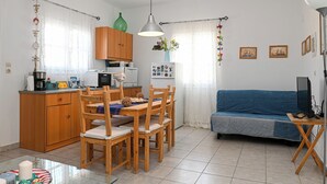 A compact living space with a dining area, kitchenette, and a sofa. - Santorini View House (Santorini)