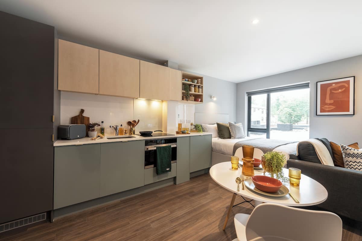 Une cuisine moderne avec des meubles gris, un coin repas avec une table blanche et un canapé agrémenté de coussins.