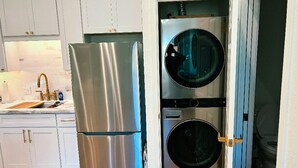 Une cuisine compacte équipée d’un réfrigérateur en acier inoxydable, d’un lave-linge et d’un évier avec un robinet.