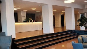 Un hall d’entrée moderne avec un comptoir d’accueil, un escalier et des espaces de détente.