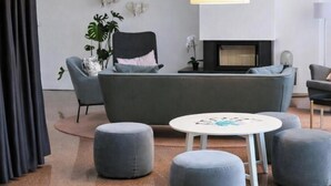 Un salon moderne avec un canapé, des poufs, une table ronde et une cheminée.