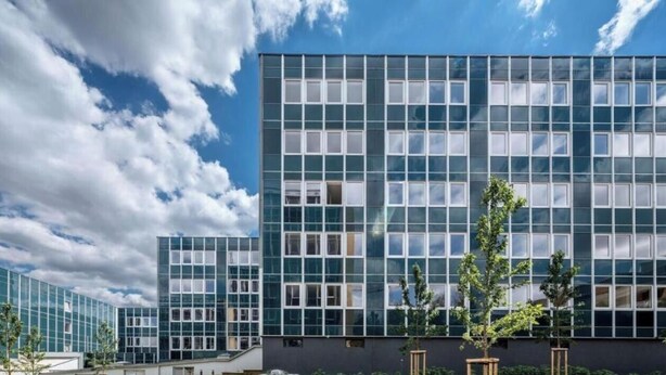 Un bâtiment moderne doté d’une façade en verre, de nombreuses fenêtres et d’un toit plat.