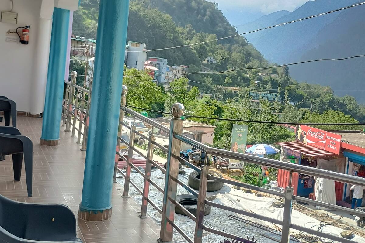 Un balcon orné de piliers bleus, une enseigne Coca-Cola et une vue sur un paysage vallonné.