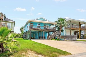 Una zona residencial costera con dos casas frente a la playa, que tienen balcones y un porche cubierto.