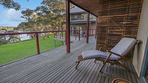 A wooden deck with a lounge chair, a view of a house, and a grassy area. - F&E Lakes Escape - East: A peaceful retreat nestled along the lakefront (Paynesville)