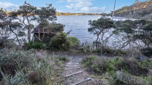 A rustic wooden structure by a lake with a clear path leading to it. - F&E Lakes Escape - East: A peaceful retreat nestled along the lakefront (Paynesville)
