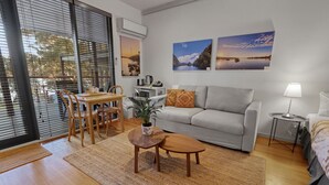 Un soggiorno moderno con un divano grigio, un tavolo da pranzo in legno e due quadri appesi al muro.