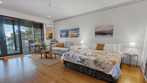 Camera da letto moderna con un ampio letto, un'area pranzo e vista attraverso il portafinestra scorrevole.