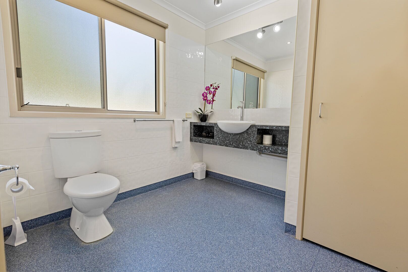 Een badkamer met toilet, wastafel en raam.