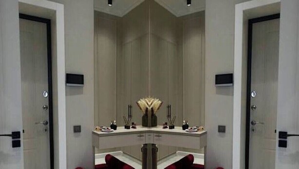 A modern bathroom with a large mirror, two red chairs, and a vanity with a sink and mirror.