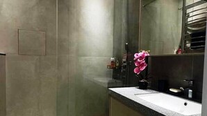 A modern bathroom with a large mirror, a white sink, and a green mat on the floor.