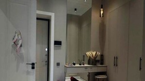 A modern bathroom with a marble floor, a red chair, a sink, and cabinets.