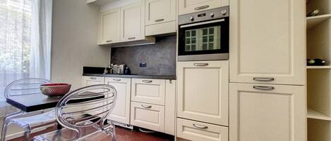 A kitchen with white cabinets, a black oven, and a clear chair.