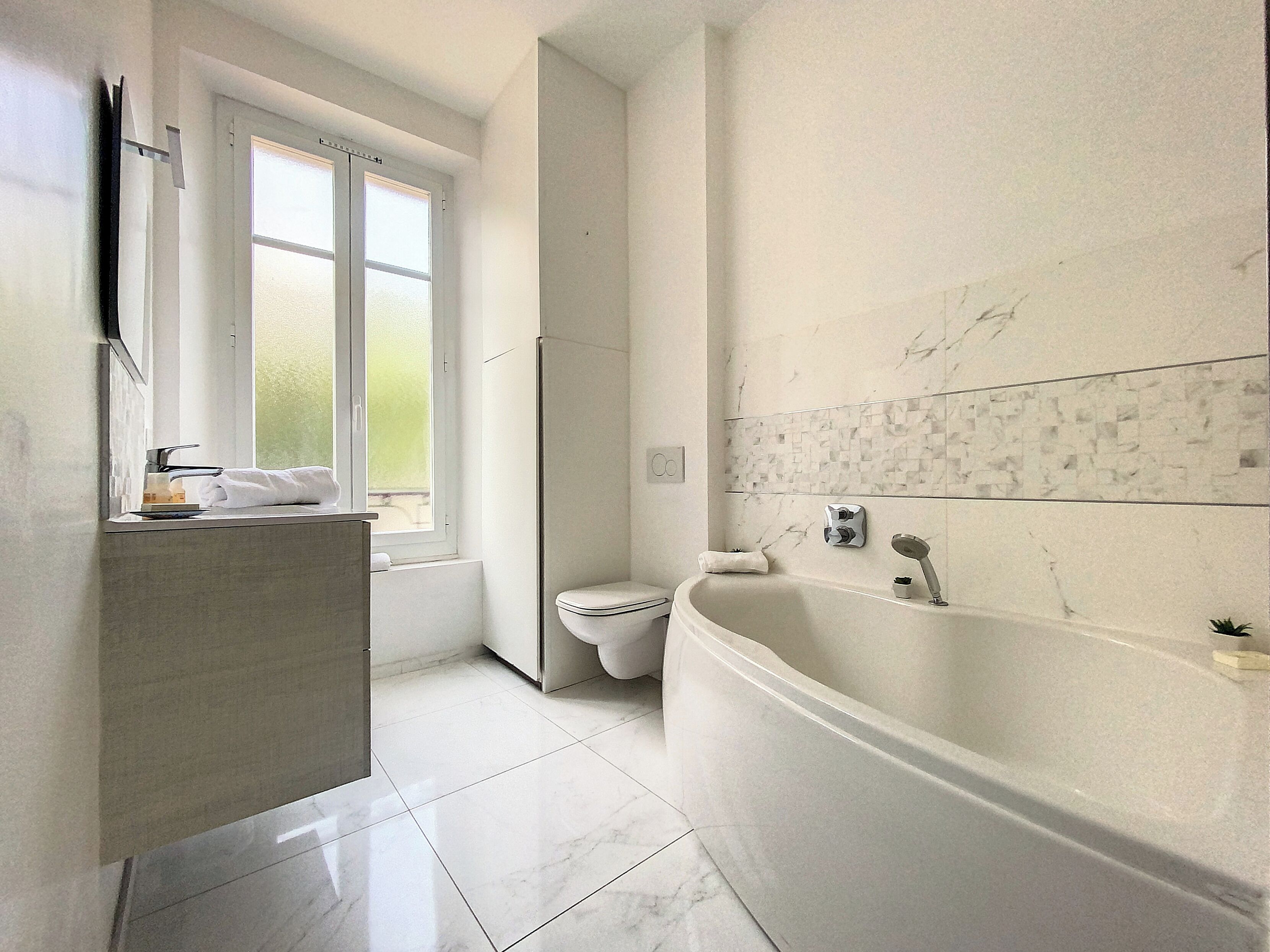 A modern bathroom with a bathtub, toilet, and sink.