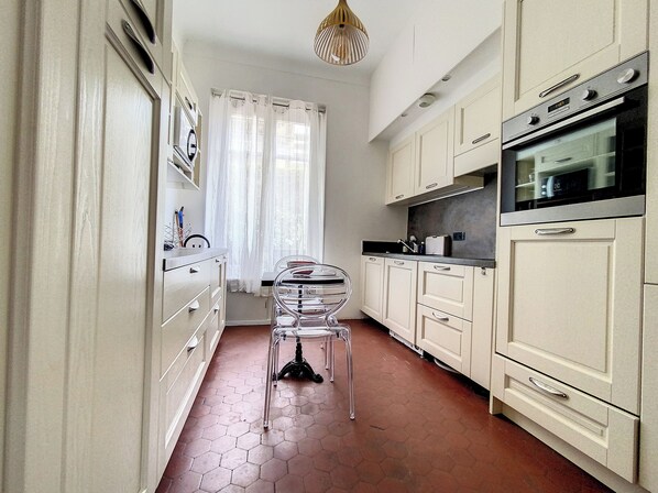 A kitchen with white cabinets, a black countertop, and a hexagonal tile floor.