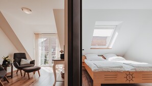 A bedroom with a sloped ceiling, a bed with a wooden headboard, a desk, and a chair. - Apartment 'Shenandoah' with Private Balcony, Shared Garden and Wi-Fi (Baltrum)