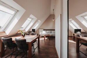 Um loft moderno com claraboias, uma área de jantar com cadeiras, um sofá e uma televisão.