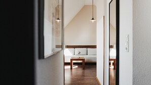 A room with a wooden floor, a sofa, a small table, and pendant lights. - Apartment 'Lord Nelson' with Shared Terrace, Shared Garden and Wi-Fi (Baltrum)