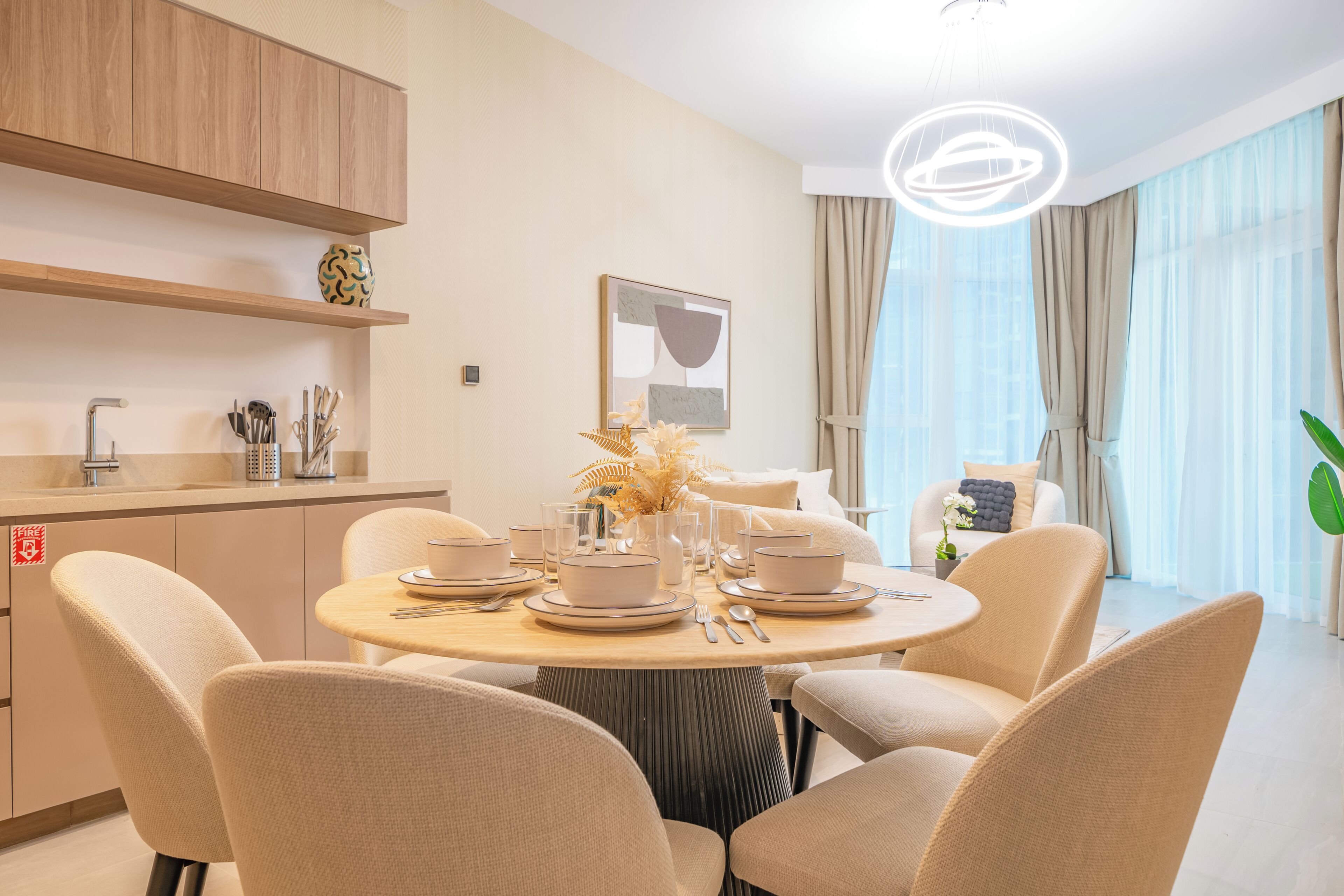 A modern dining area with a round table, beige chairs, and a minimalist decor.