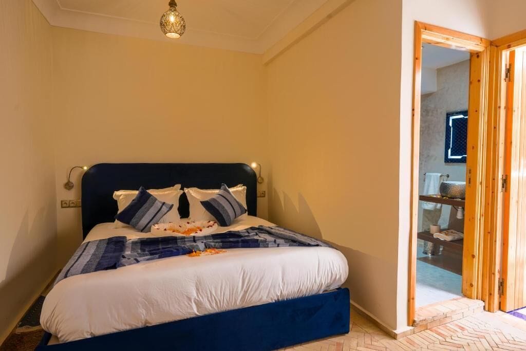 Un dormitorio con cama, una puerta de madera y una lámpara en el techo.