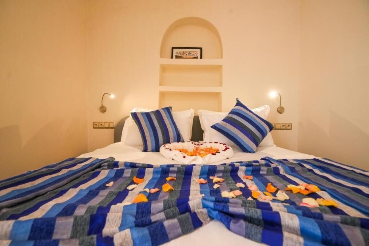 A bed with striped bedding, a decorative plate with flowers, and wall-mounted shelves.
