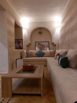 A living room with a sofa, a coffee table, and a TV.