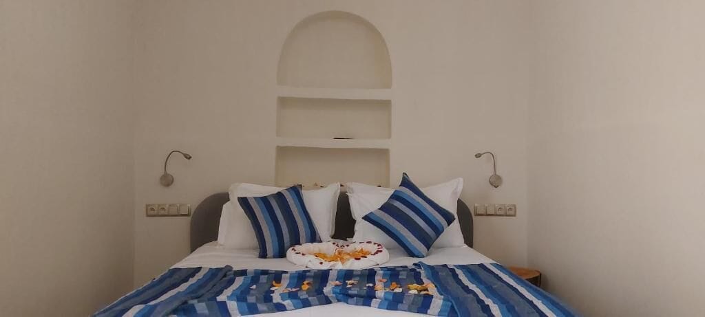 Un lit recouvert d’une couvre-lit à rayures bleues et blanches, deux oreillers à rayures bleues et un objet décoratif posé sur le lit.