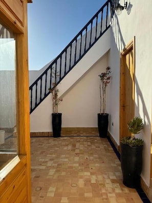 A staircase with black railings, potted plants, and a tiled floor.