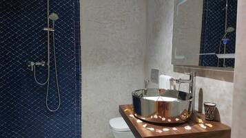 Ein Badezimmer mit einem modernen Waschbecken, einer Dusche und einem Spiegel.