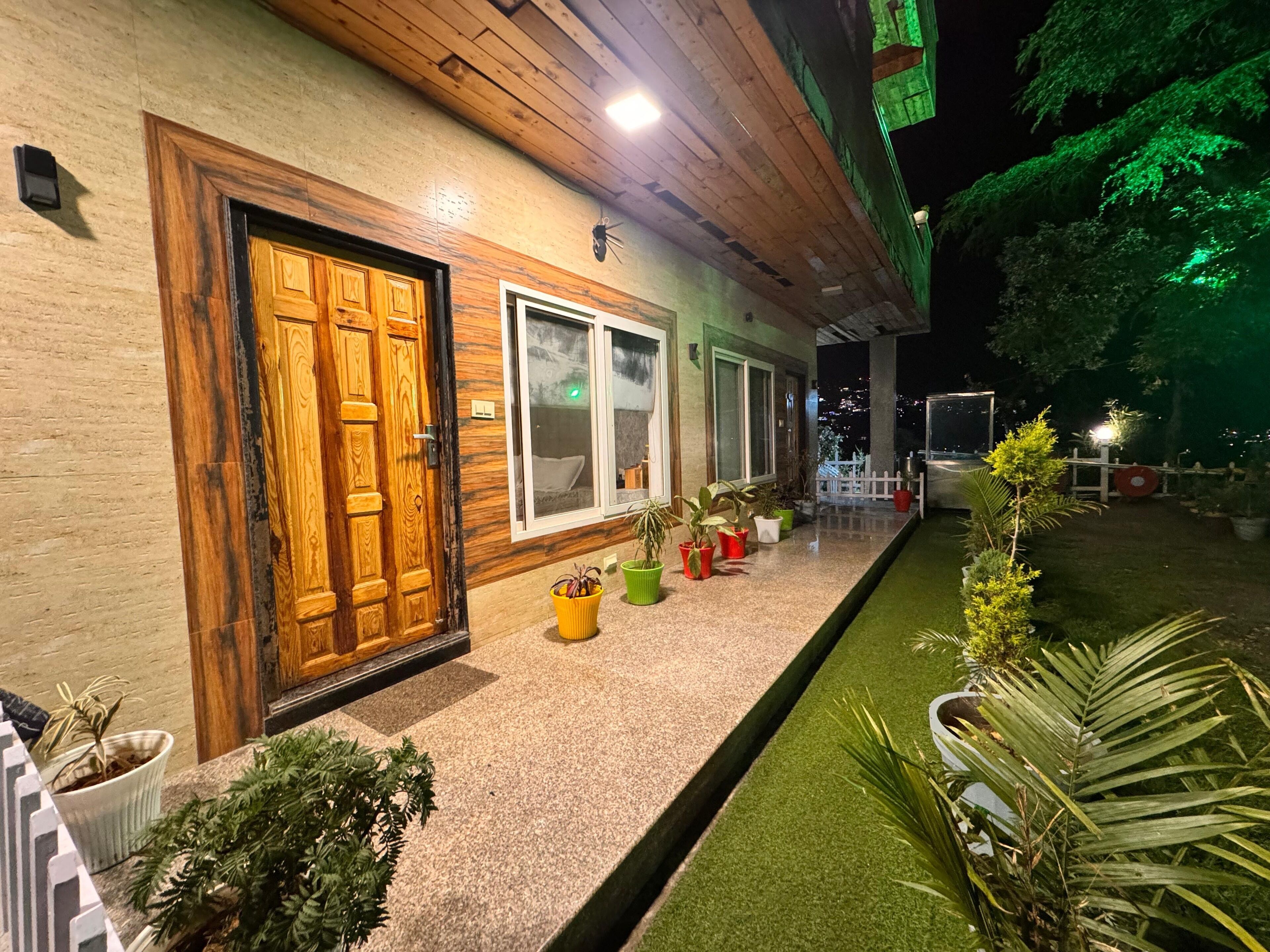 A building with a wooden door and windows, a paved pathway, and potted plants.