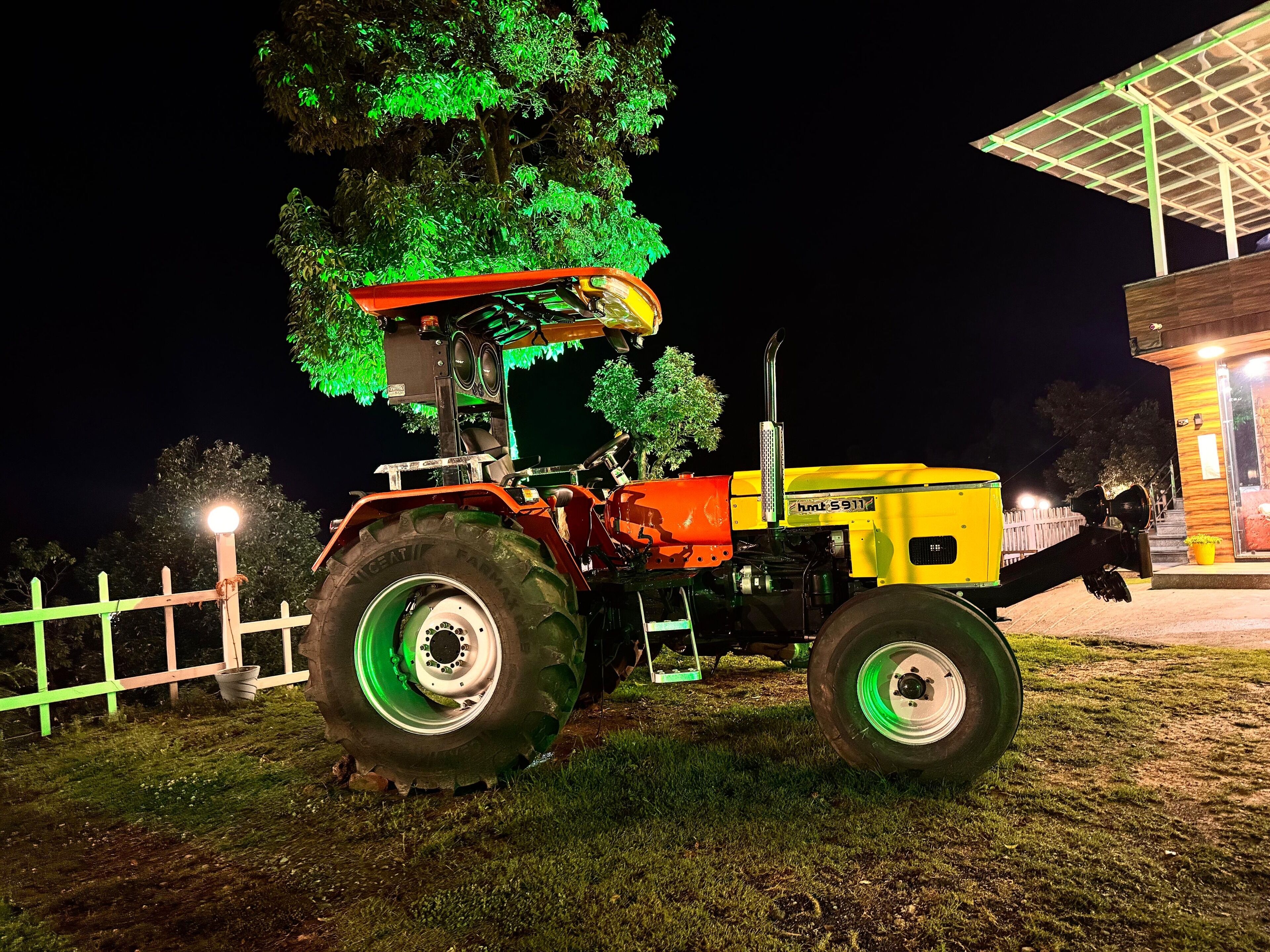 Un tracteur est garé la nuit près d’un bâtiment doté d’une zone abritée.