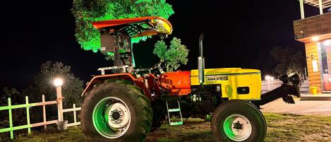 A tractor parked at night near a building with a covered area.