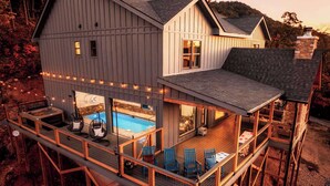 A two-story house with a balcony, a pool, and outdoor seating. - Incredible 180 VIEWS! | Luxury Lodge | Indoor Pool (Sevierville)