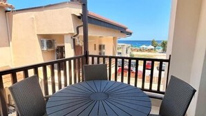 Un balcone con un tavolo rotondo e quattro sedie, con vista su una spiaggia e altri edifici.