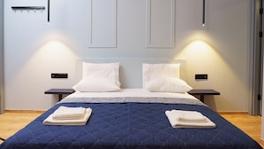 A modern hotel room with a large bed, two bedside tables, and a wall-mounted light fixture. - Sani Deluxe Suite Home (Athens)