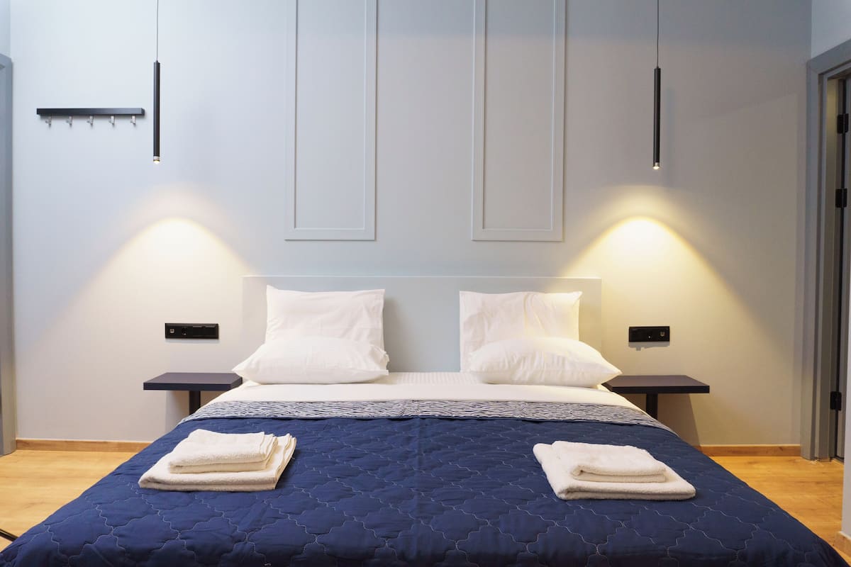 A modern hotel room with a large bed, two bedside tables, and a wall-mounted light fixture.