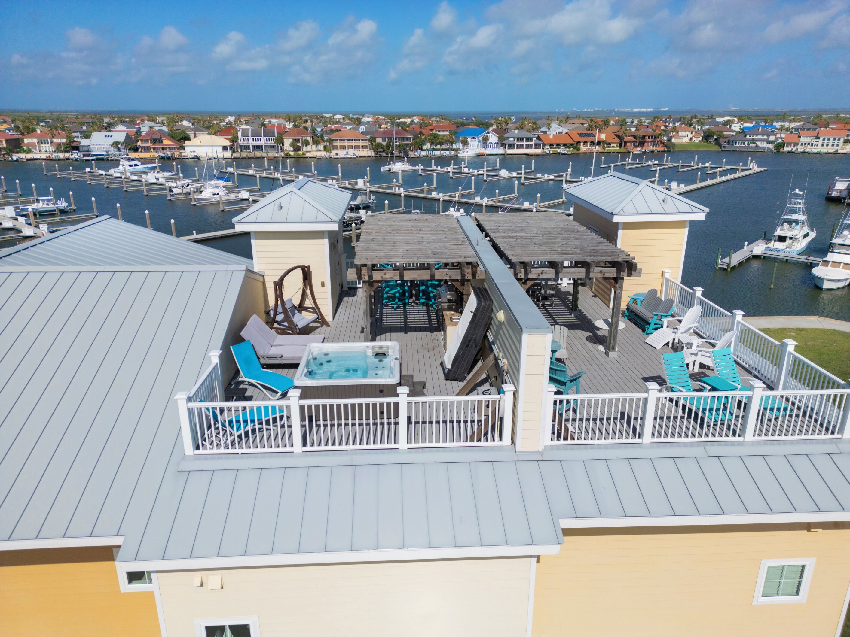 A marina with boats docked, a pool area with lounge chairs, and a view of the surrounding neighborhood.