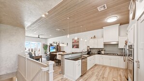 A spacious kitchen with wooden flooring, white cabinetry, and a central island.