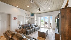 A spacious living room with a leather sofa, wooden coffee table, and a TV on a wooden cabinet.