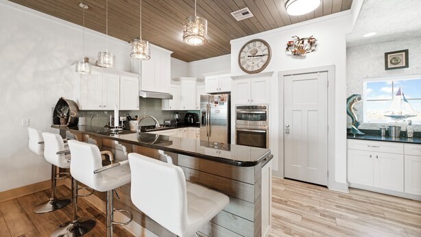 A modern kitchen with white cabinets, stainless steel appliances, and a central island with bar stools.