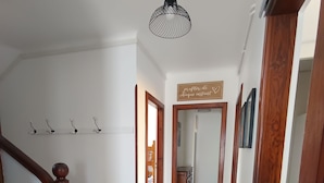 A hallway with a wooden staircase, a hanging pendant light, and a sign on the wall. - Villa Laurier-Rose, Swimming pool, Petanque, 16 pers, Near lake, Ocean, Town center (Parentis-en-Born)